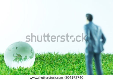 Abstract Background : Blur Miniature Business Man Looking To Glass Earth On Green Artificial Grass