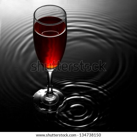 Red wine glass on water ripples background