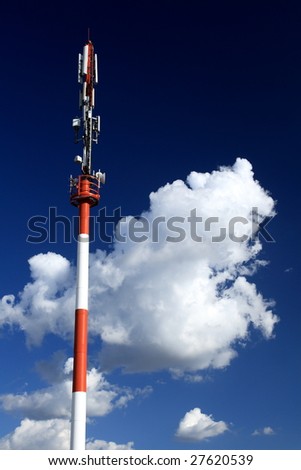 Cellular tower against blue sky and clouds
