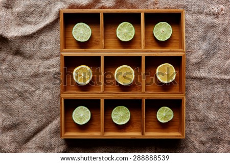 Lemon and lime cut into slices and laid in size in square wooden form with a cell for each lobule
