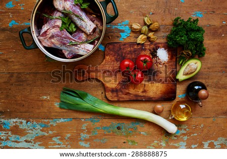 lamb marinated in a deep dish with spices and herbs, lies next to the board for cutting vegetables, olive oil and the marinade sauce, tomatoes and avocados are a garnish for dishes
