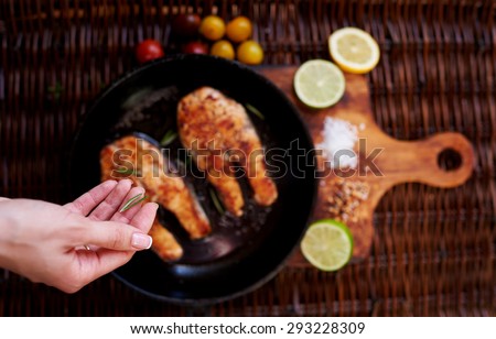 Girl salts Two red fish steak fried in a frying pan for two persons, is a pan on a wooden board close tomatoes and slices of lemon and lime