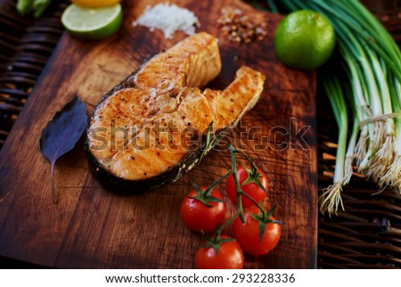 Big salmon steak baked in the oven until golden brown lying on a wooden surface, for serving fish perfect tomatoes chives and lemon, cook restaurant cooked piece of salmon on the grill