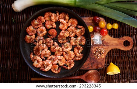 Shrimp fried in soy sauce with garlic in olive oil first press, served in a cast iron skillet, poured lemon juice, Cherry tomatoes yellow and red complement the composition with shrimp and parey