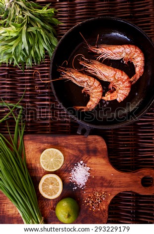 The best snack to beer, prawns, grilled or rapid fire in a deep frying pan. Three large tiger shrimps lie in a deep bowl for dikustatsii near lemon and lime and rosemary