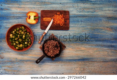 On the wooden table is a vintage small pan with ground beef, standing next to pottery with cauliflower garnish