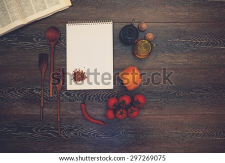 On a dark wooden table lay a large book pkulinarnaya next note pad on the table laid out the ingredients for the salad