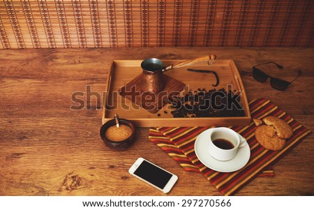 Example serving coffee for the coffee break in a restaurant or a cafe on the spacing is a cup of coffee cezve stands next to a sprig of vanilla flavor, oatmeal cookies
