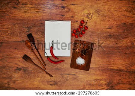 On the table is a notebook to record interesting new recipes A wooden cutting board next to her and a large sea salt and pepper