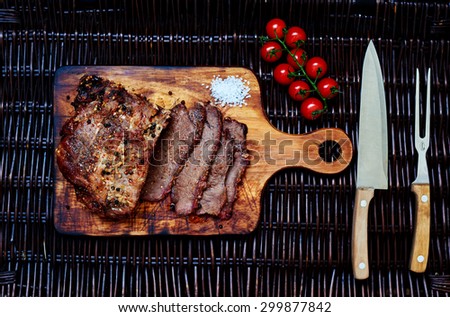 A large piece of pork tenderloin baked in the oven housewife, before serving, cut into portions small steaks, lie next to the tomatoes in the salad
