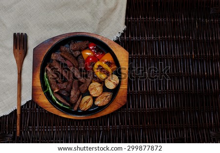 The meat cut into small pieces, juicy and tasty, served in a small cast iron pan with vegetables