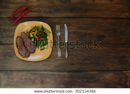 Cook Italian restaurant two steaks cooked pork tenderloin with vegetables. On the table served dinner of tender lamb, served with meat vegetable ragout