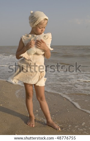 The girl on seacoast with a toy small fish in hands, toy handmade by photographer.