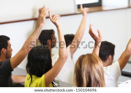 students put hand up in class room
