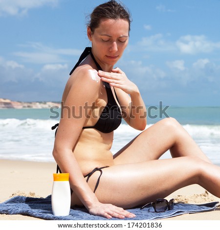 attractive woman putting lotion on her body