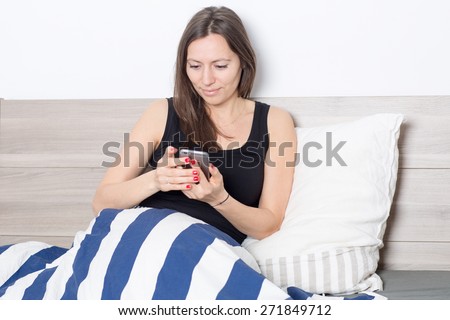 Brunette woman using dating app in bed