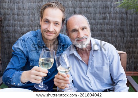 Father and son in garden drinking wine