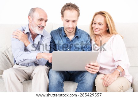 Elderly son looks at a laptop with his parents