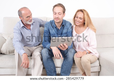 Elderly son shows something on a tablet with his parents