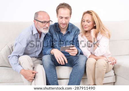 Elderly son looks at a phone with his parents