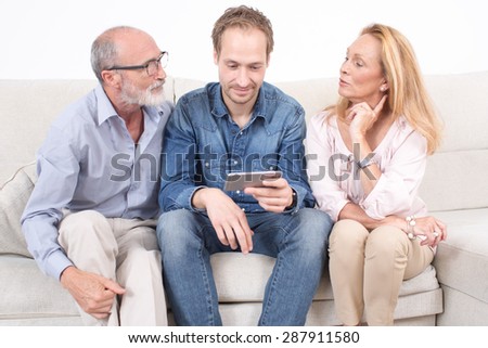 Elderly son shows something on a phone to his parents
