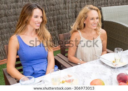 Two women listening to a conversation while having food in garden