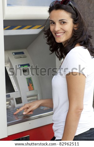 Good-looking latin woman enters the PIN number at the ATM