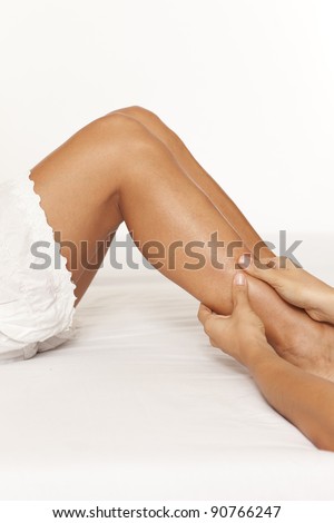 Massage of a woman calf muscle on white background