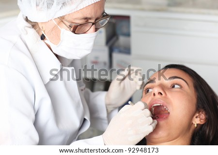 Older dentist with latin woman as patient