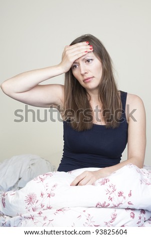 Young caucasian woman having headache sitting in bad
