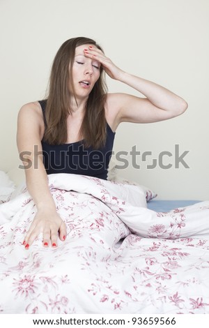 Young caucasian woman having headache sitting in bad