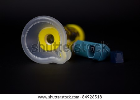 An inhaler with spacer unit for children that have asthma. Shot against black background with plenty of room for text. Studio Isolation.