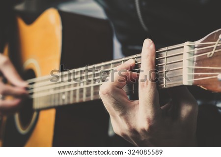 close-up, hand playing on acoustic guitar, chord F# major position