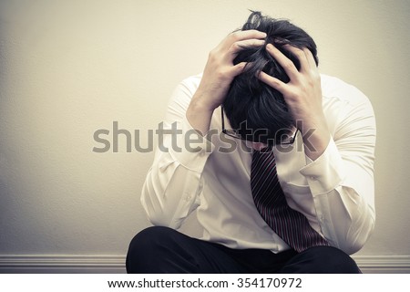 Depressed young asian business man holding his head in hand and sitting on floor, unemployed, dismiss