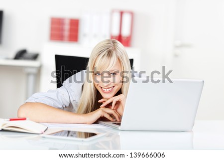 Happy female laying her chin on the table with laptop and tablet