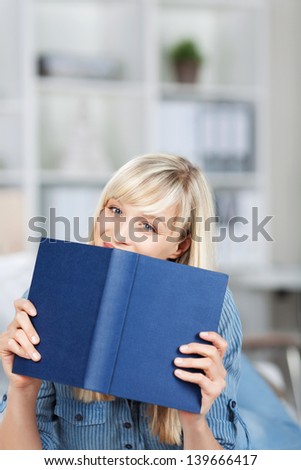 Caucasian woman holding a blue book over the blurred living room