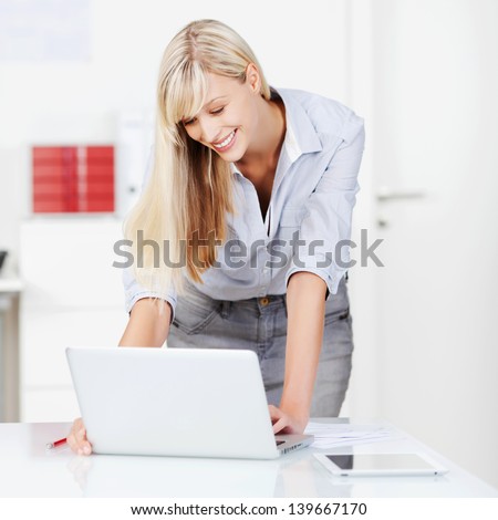 Portrait of smiling woman surfing the internet using laptop on table