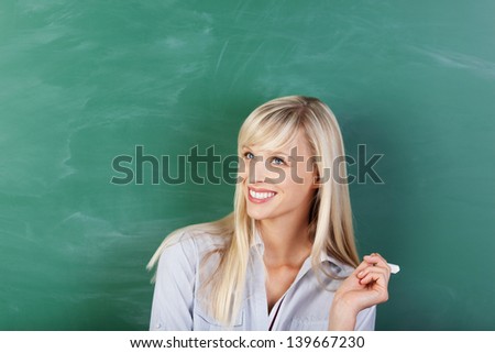 Blond woman looking up and thinking over the green board