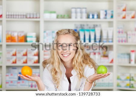 Young female pharmacist with apple and orange in pharmacy