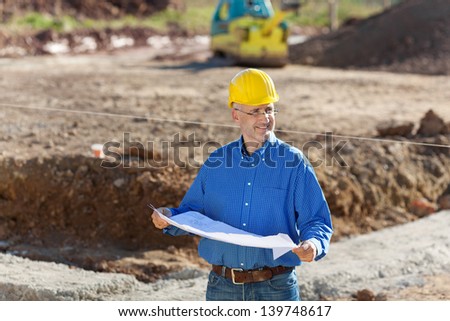 Businessman examining blueprint while standing at construction site