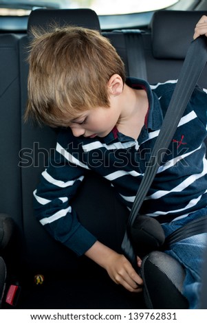 Young little boy buckled up with seatbelt inside the car