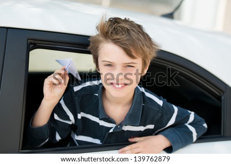 Young boy playing with paper airplane inside the car