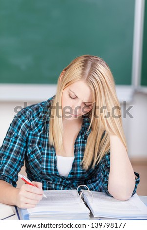 Confused female student reading documents at classroom desk
