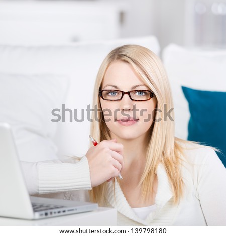 Young blond woman sit on the sofa with laptop in house