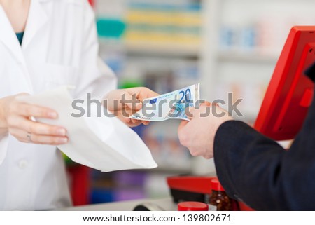 Cropped image of pharmacist receiving money from customer for medicines