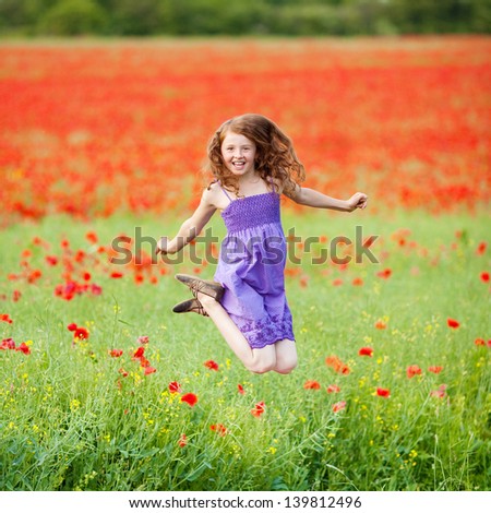 Cheerful young female jumping in a fresh flower field