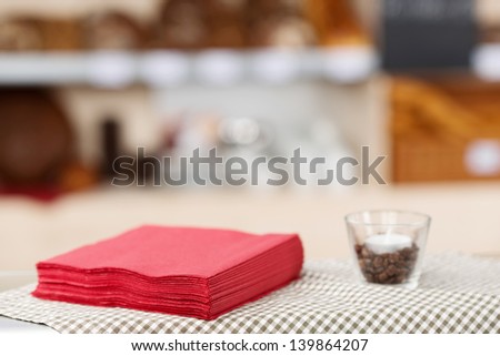 Closeup of stacked tissue papers and tealight candle in glass on coffee shop table