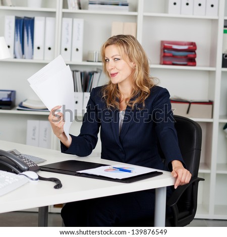 Mid adult businesswoman fanning herself with documents
