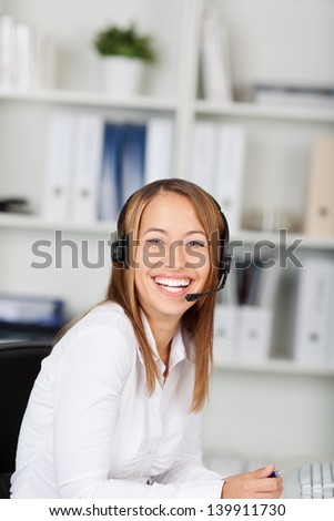 Portrait of laughing female customer service executive sitting at office desk