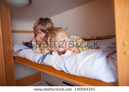 Portrait of happy young boy with brother lying on bunk bed at home